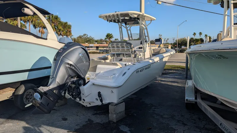 Slide: The Image of 2025 Key West 239 FS boat with outboard motor, parked outdoors. - 2