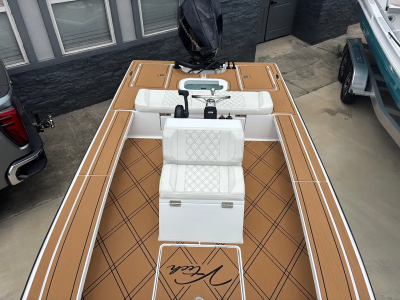 Slide: The Image of 2024 Vtech 18 FLATS boat with tan deck and white seating, docked near a building. - 10