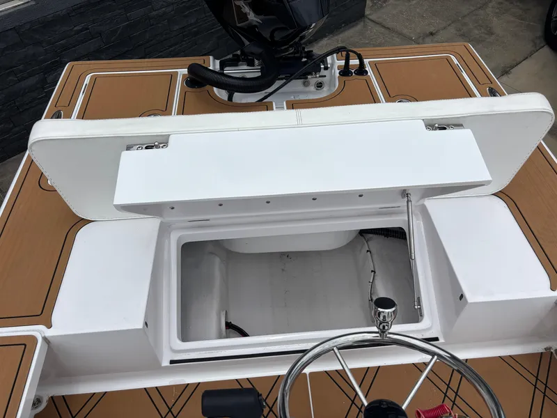 Slide: The Image of 2024 Vtech 18 FLATS boat interior with open storage compartment and steering wheel. - 17