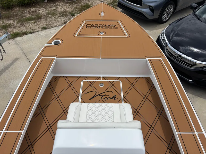 Slide: The Image of 2024 Vtech 18 FLATS boat with brown deck and white seating, parked near cars. - 6