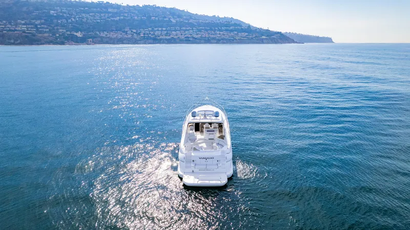 Slide: The Image of Cruisers Yachts 5370 Express 2002 on serene ocean with coastal backdrop. - 3