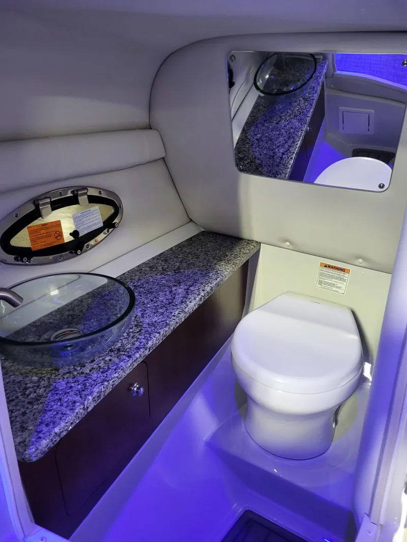 Slide: The Image of 2023 Crownline 260 SS boat bathroom with modern design, glass sink, and granite countertop. - 13