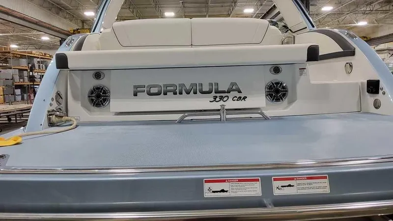 Slide: The Image of 2025 Formula 330 Crossover Bowrider boat, rear view in a warehouse setting. - 9