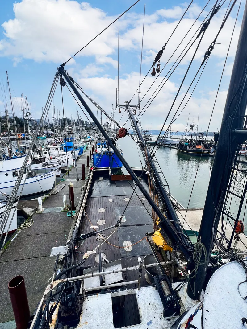 Slide: The Image of 1980 custom fishing vessel docked at a busy marina under a partly cloudy sky. - 17