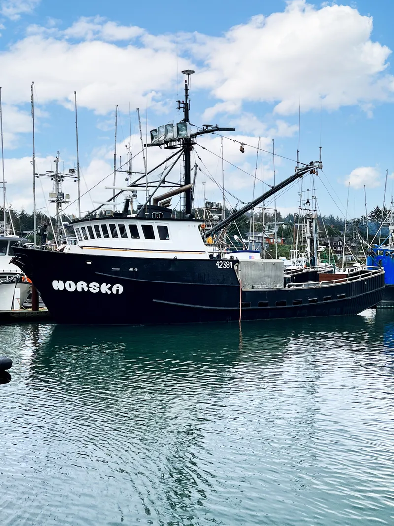 Slide: The Image of Custom 1980 fishing vessel "Norska" docked in a marina under a partly cloudy sky. - 26