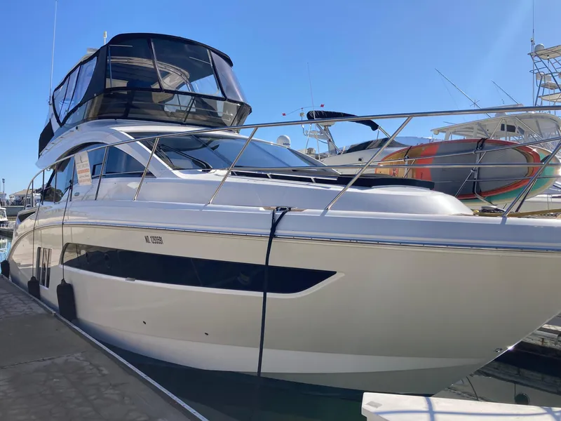 Slide: The Image of 2018 Sea Ray Fly 510 yacht docked at marina under clear blue sky. - 1