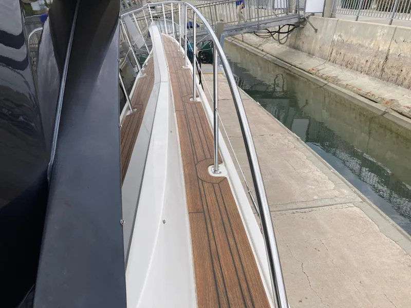 Slide: The Image of 2018 Sea Ray Fly 510 yacht docked, showcasing sleek deck and railing design. - 15