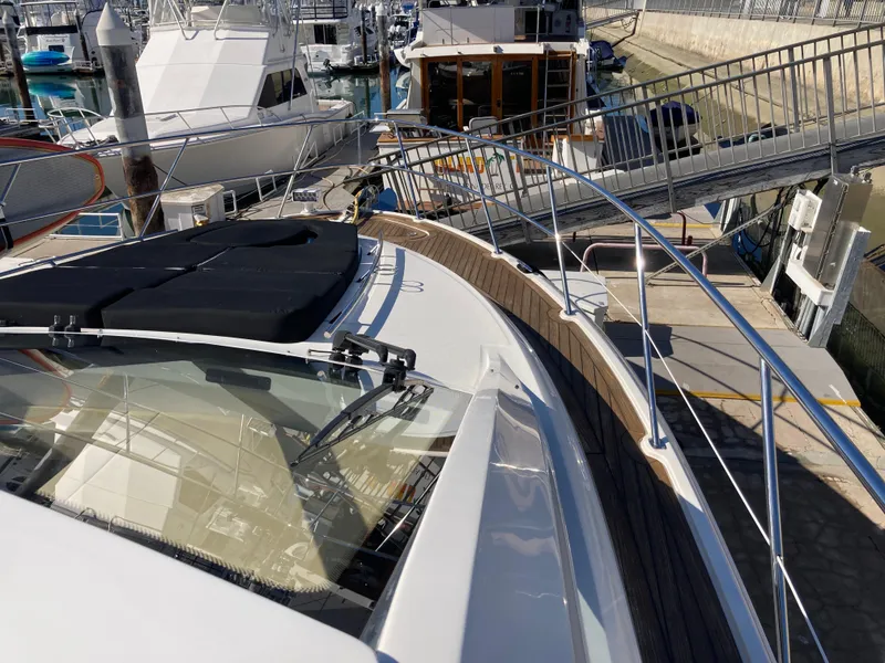 Slide: The Image of 2018 Sea Ray Fly 510 yacht docked at marina, showcasing sleek design and spacious deck. - 16