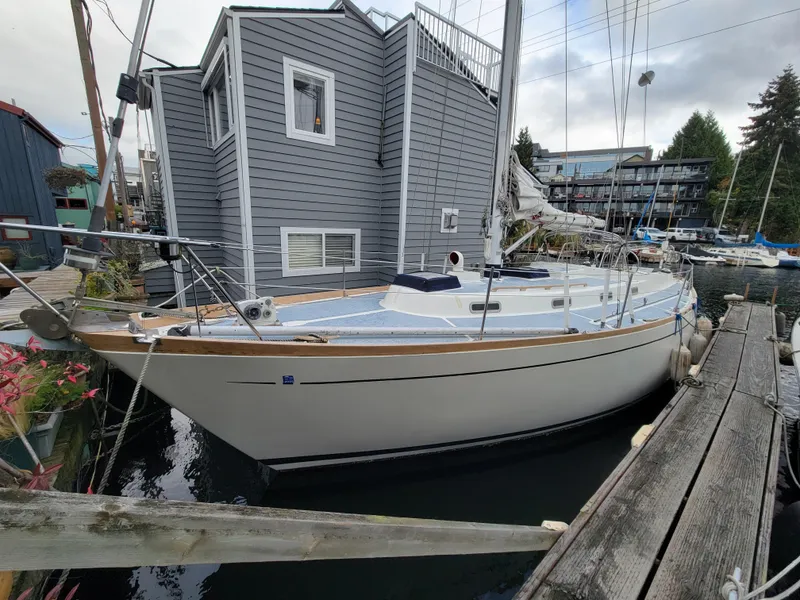The Image of 1978 Fuji 40 sailboat docked beside a modern houseboat. - 0