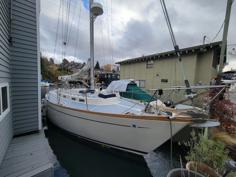 Slide: The Image of 1978 Fuji 40 sailboat docked beside waterfront buildings under cloudy sky. - 1
