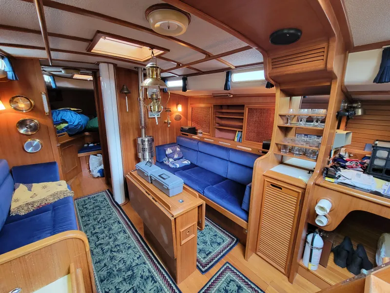 Slide: The Image of Cozy 1978 Fuji 40 yacht interior with blue seating, wooden accents, and nautical decor. - 19