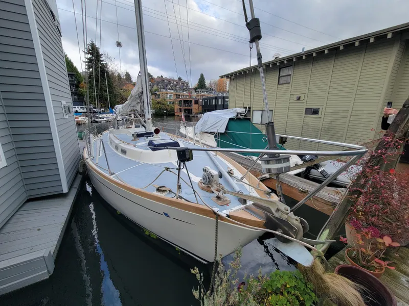 Slide: The Image of 1978 Fuji 40 sailboat docked beside houseboats in a marina setting. - 2