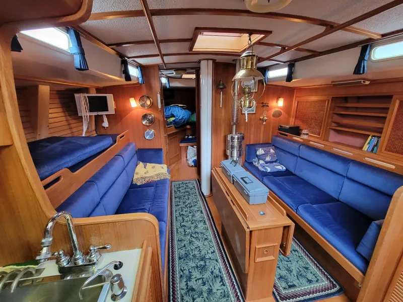 Slide: The Image of Cozy 1978 Fuji 40 yacht interior with blue seating, wood paneling, and nautical decor. - 20