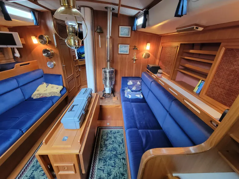 Slide: The Image of Cozy 1978 Fuji 40 yacht interior with blue seating, wooden accents, and nautical decor. - 23