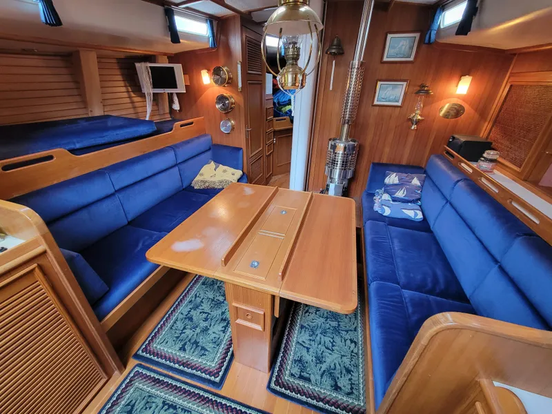 Slide: The Image of Cozy 1978 Fuji 40 yacht interior with blue seating, wooden table, and nautical decor. - 25