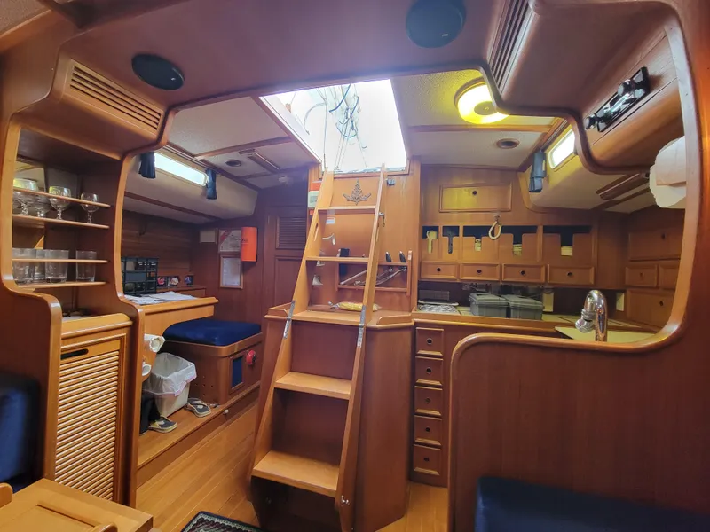 Slide: The Image of Interior of a 1978 Fuji 40 sailboat, featuring wooden cabinetry and a central ladder. - 27