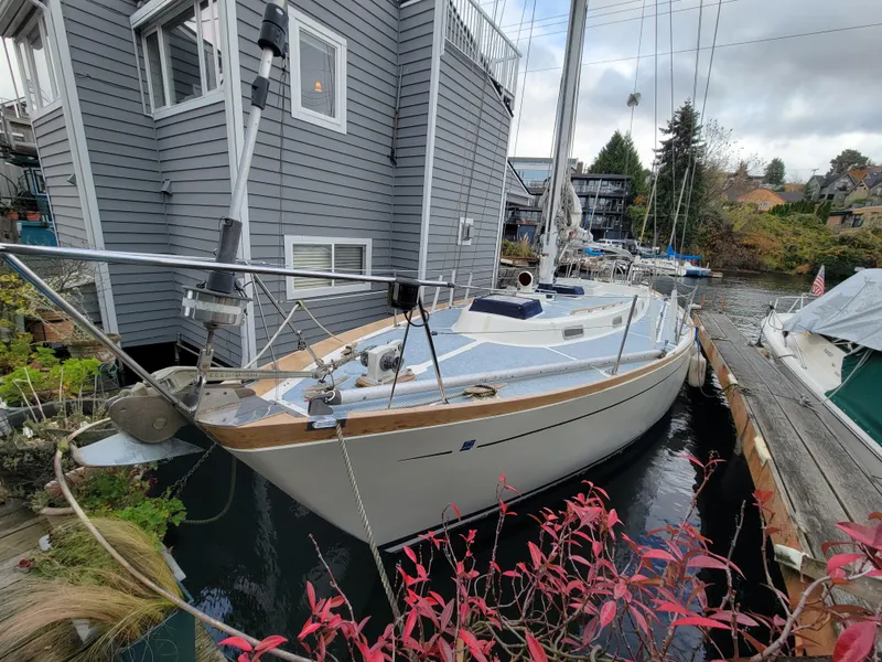 Slide: The Image of 1978 Fuji 40 sailboat docked beside a gray houseboat, surrounded by lush greenery. - 3