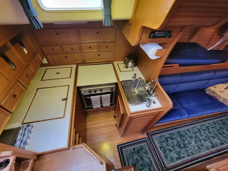 Slide: The Image of Cozy 1978 Fuji 40 yacht interior with wooden cabinetry and compact kitchen area. - 9