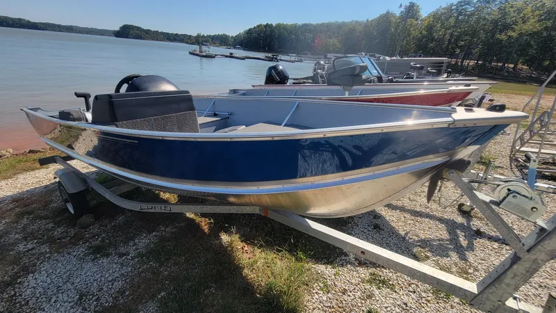 Slide: The Image of 2023 Lund SSV 16 Side Console boat on trailer by a lake. - 3