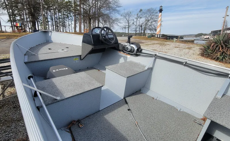 Slide: The Image of 2023 Lund SSV 16 Side Console boat, docked near a lighthouse, with a steering console. - 5