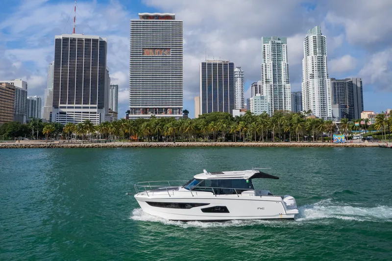 Slide: The Image of 2019 Jeanneau NC 1095 cruising in urban waterfront setting with skyscrapers. - 10