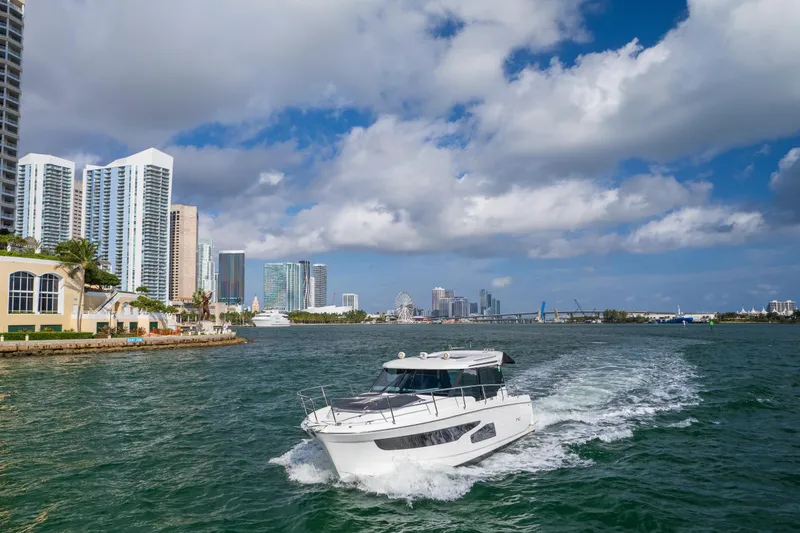Slide: The Image of 2019 Jeanneau NC 1095 cruising near city skyline under cloudy sky. - 13