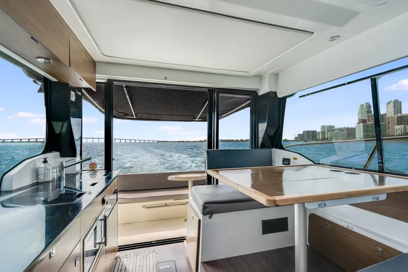 Slide: The Image of Interior view of 2019 Jeanneau NC 1095 yacht with kitchen and dining area overlooking water. - 29
