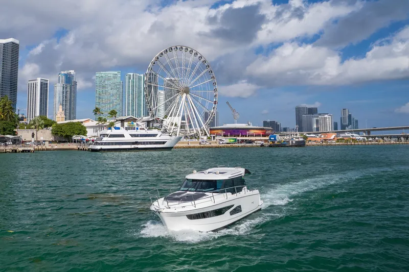 Slide: The Image of 2019 Jeanneau NC 1095 cruising near a city skyline and Ferris wheel. - 5