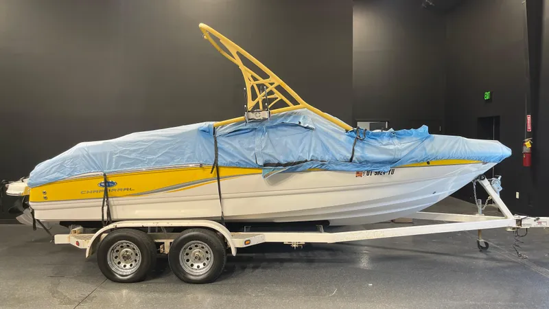 Slide: The Image of 2005 Chaparral 210 SSi boat on trailer, covered with blue tarp, in indoor setting. - 26