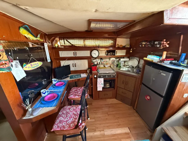Slide: The Image of 1984 Sea Ray 390 Express Cruiser interior with kitchen, dining area, and wooden cabinetry. - 14
