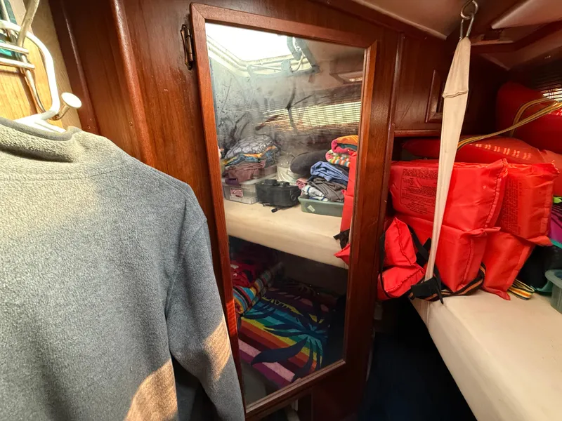 Slide: The Image of 1984 Sea Ray 390 Express Cruiser cabin with mirror, life jackets, and storage shelves. - 17