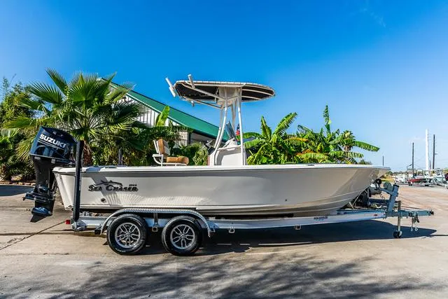 Slide: The Image of 2025 Carolina Skiff 23LX boat on trailer, parked near tropical plants. - 1