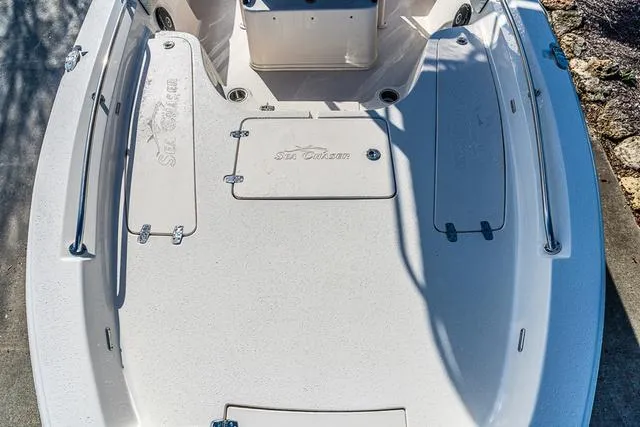 Slide: The Image of 2025 Carolina Skiff 23LX boat deck with storage compartments and sleek design. - 10