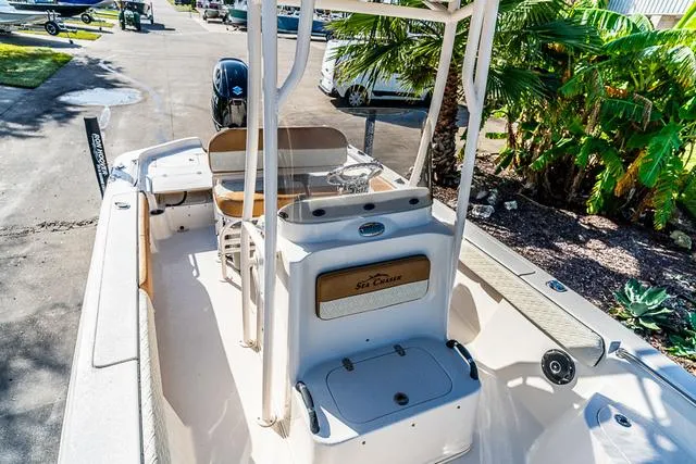 Slide: The Image of 2025 Carolina Skiff 23LX boat interior with seating and console, parked near palm trees. - 13
