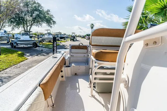 Slide: The Image of 2025 Carolina Skiff 23LX boat interior with seating, parked outdoors under clear skies. - 15