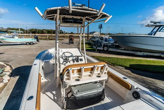 Slide: The Image of 2025 Carolina Skiff 23LX boat with center console and T-top in a marina setting. - 18
