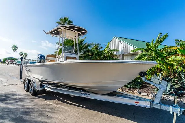 Slide: The Image of 2025 Carolina Skiff 23LX boat on trailer, sunny day, palm trees in background. - 2