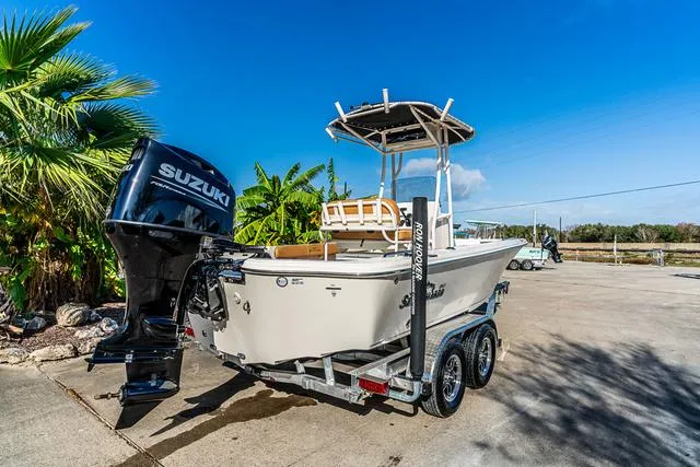 Slide: The Image of 2025 Carolina Skiff 23LX boat on trailer with Suzuki outboard motor, parked outdoors. - 3