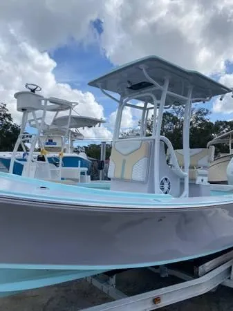 Slide: The Image of 2025 Exuma 22 CC boat with T-top, light blue and white design, on trailer. - 3