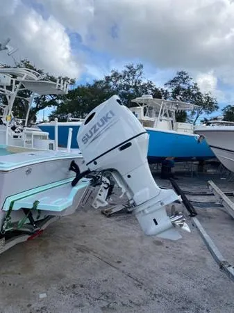 Slide: The Image of 2025 Exuma 22 CC boat with Suzuki outboard motor in a marina setting. - 7