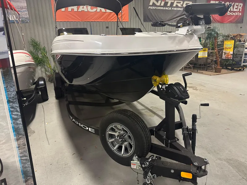 Slide: The Image of 2025 Tahoe T21 boat on trailer in showroom, featuring sleek black and white design. - 5