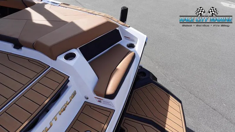 Slide: The Image of 2025 Nautique Super Air Nautique S23 boat with brown seating and deck, Race City Marine logo. - 14