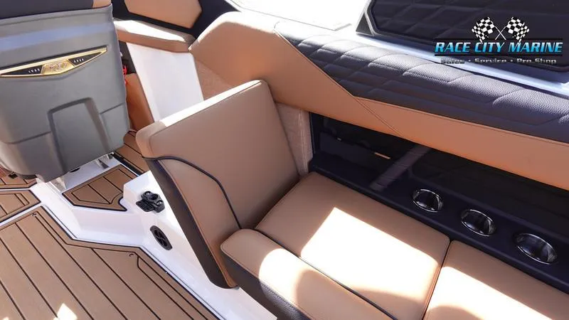 Slide: The Image of 2025 Nautique Super Air Nautique S23 interior with tan and black seating, Race City Marine branding. - 24