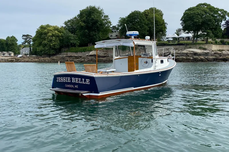 Slide: The Image of 1992 Duffy 26' boat "Jessie Belle" on calm water near a rocky shoreline. - 10