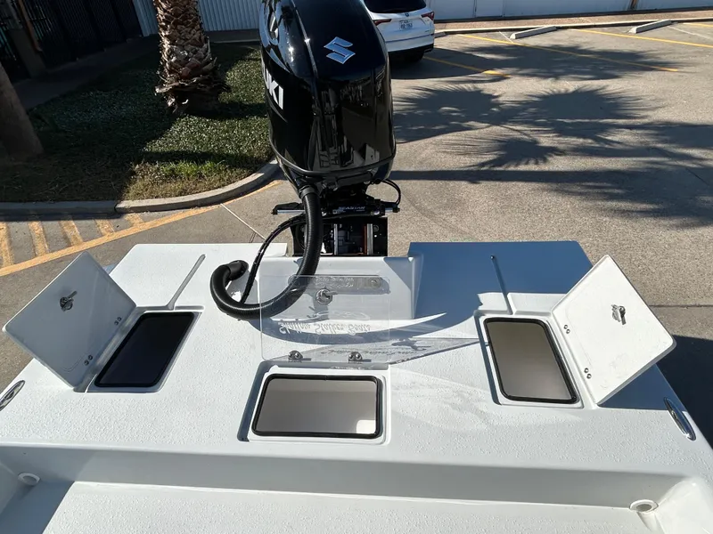 Slide: The Image of 2025 Shallow Stalker Cat 204 boat with open storage compartments and outboard motor. - 11
