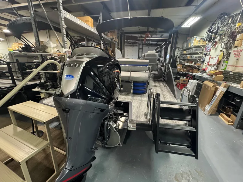 Slide: The Image of 2025 Bennington 24 LXSSB pontoon boat in a workshop, featuring a powerful outboard motor. - 13