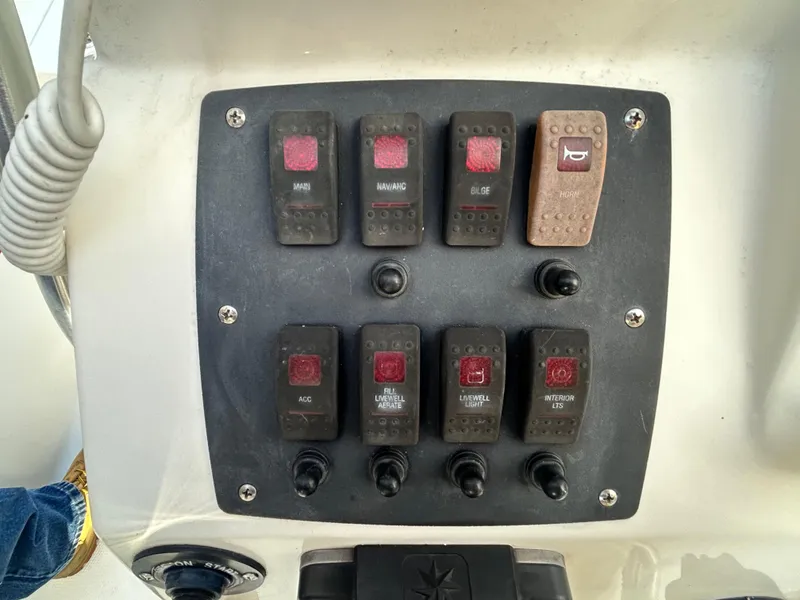 Slide: The Image of Control panel of a 2018 Mako 19 CPX boat with various switches. - 22