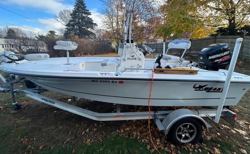 Slide: The Image of 2018 Mako 19 CPX boat on trailer with Mercury outboard motor, parked outdoors. - 4