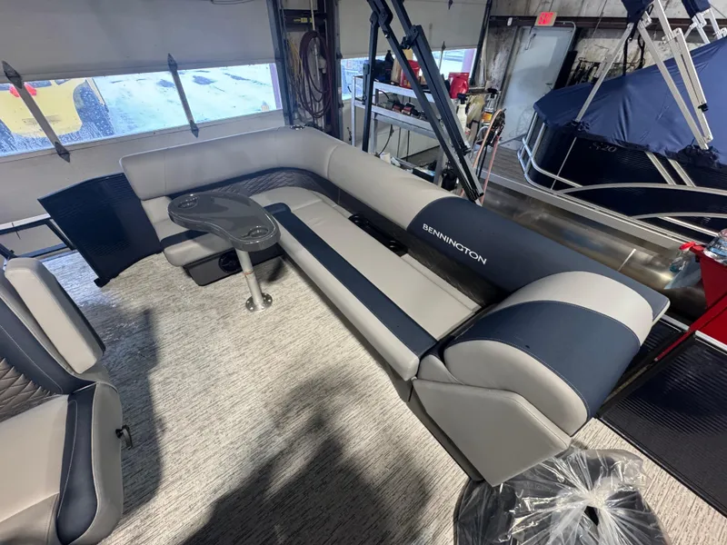 Slide: The Image of 2025 Bennington 20 SL pontoon boat interior with gray and navy seating and a small table. - 3