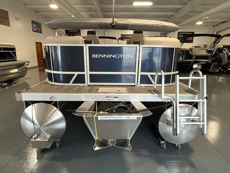 Slide: The Image of 2025 Bennington 22 SSR pontoon boat in showroom, rear view with ladder and pontoons. - 5